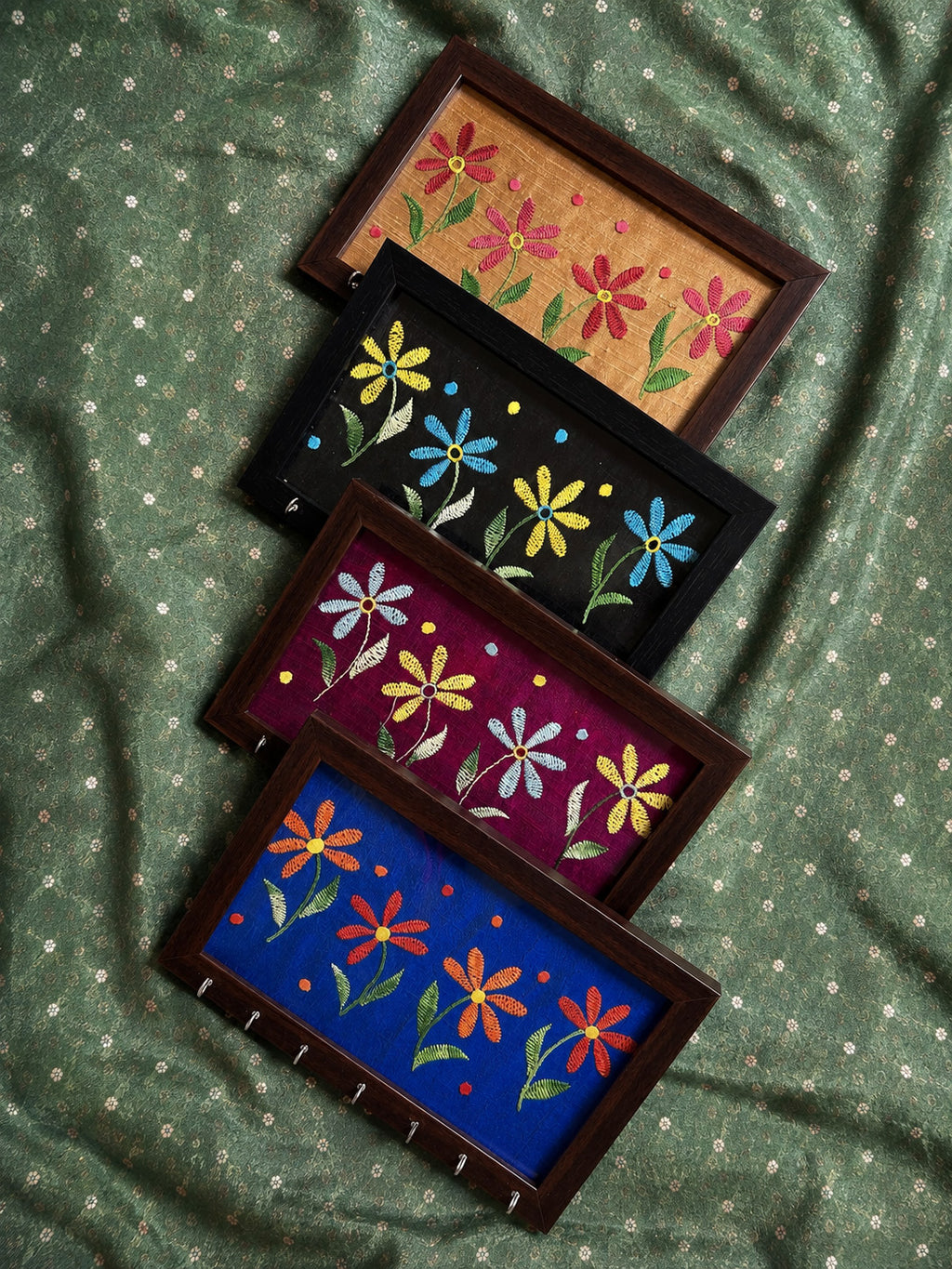 Four Aavo hand embroidered key holders stacked, showing the colour range